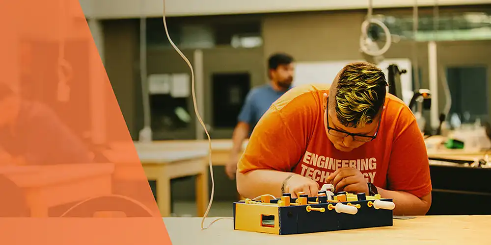 student wearing engineering technology shirt working on a project