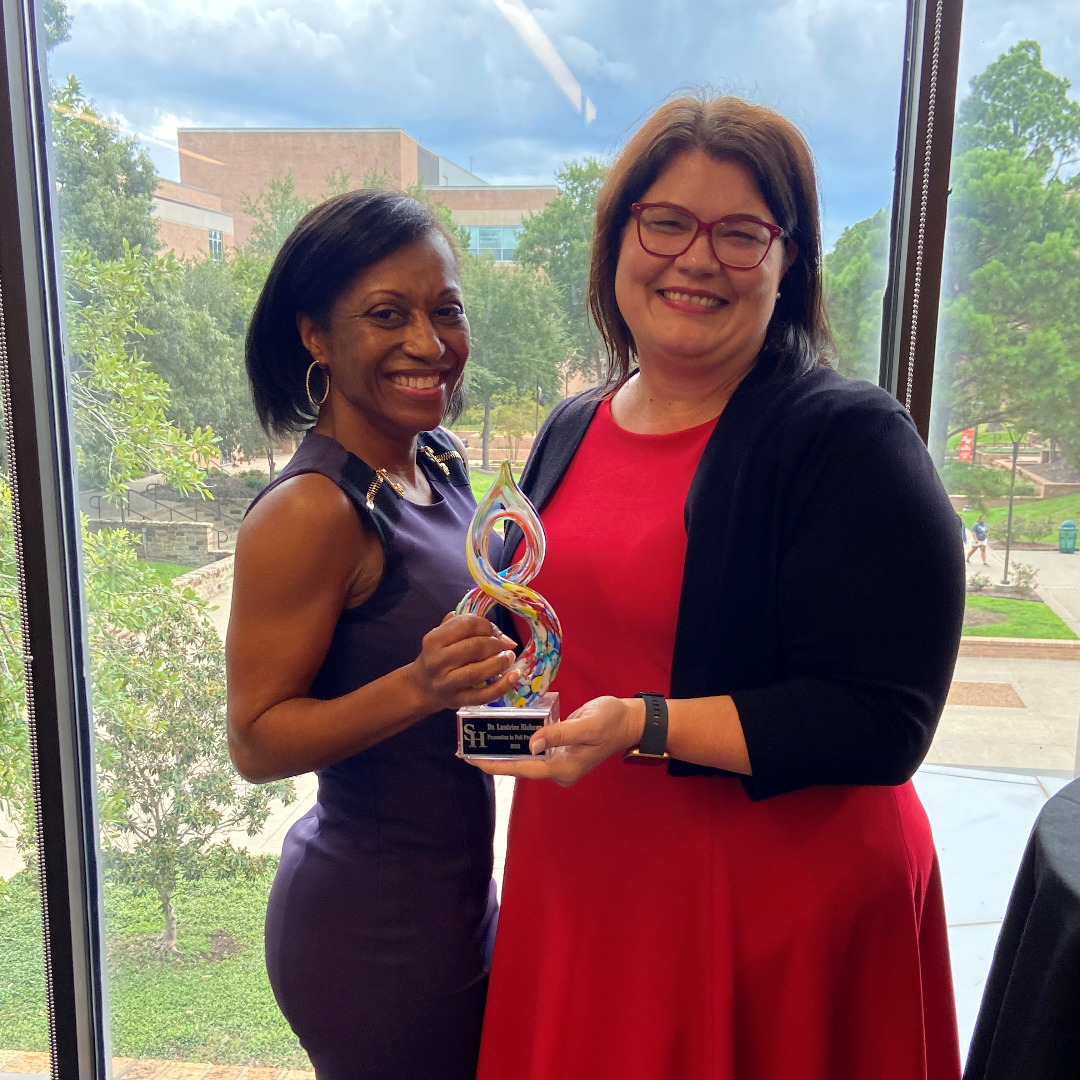 Dr. Laurtrice Nickson holding a trophy honoring her promotion