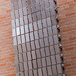 Tim Prentice's untitled kinetic sculpture of metal sheets affixed to the brick wall of the Performing Arts Center at SHSU