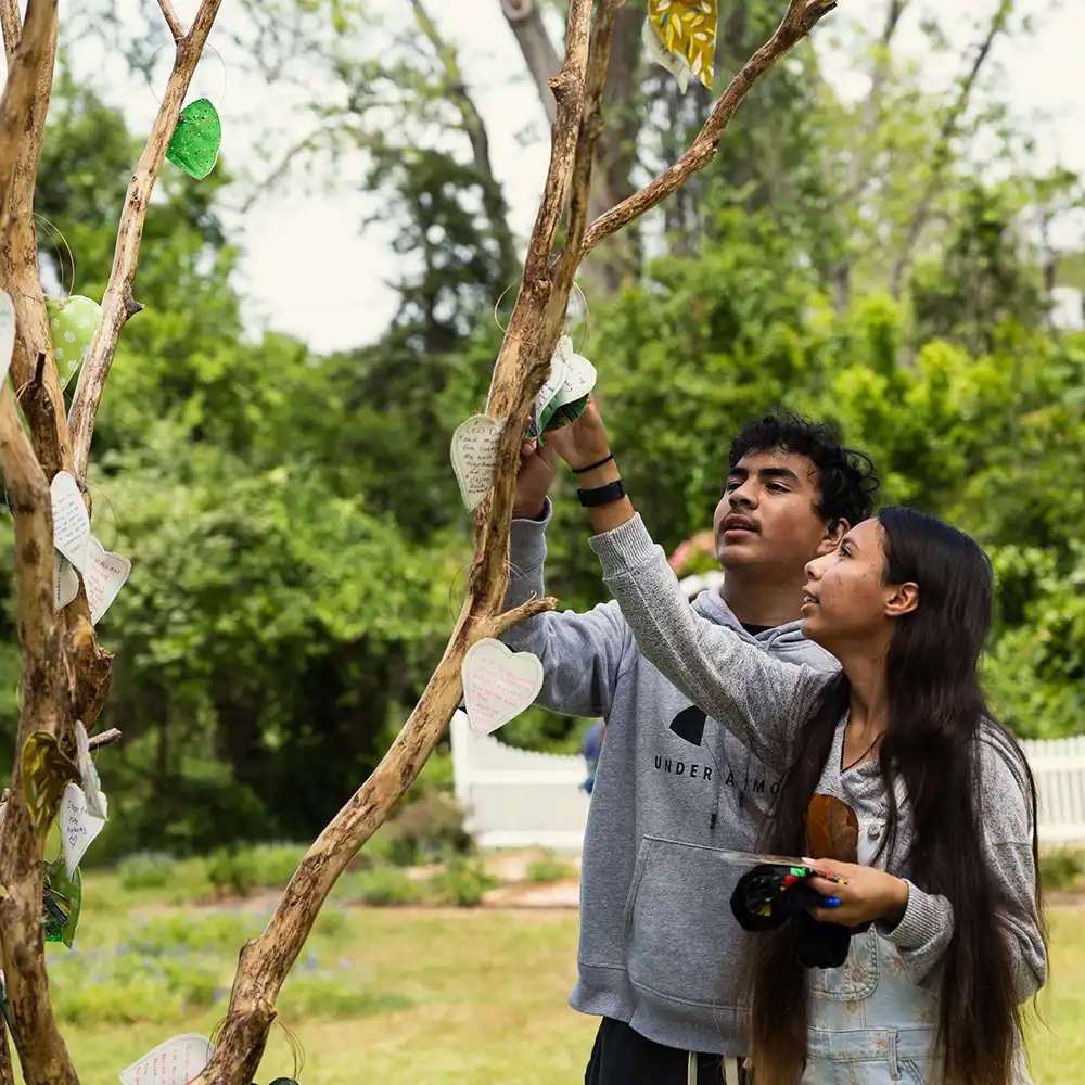 Two women looking at each other, smiling, sitting down, working on an assignment.