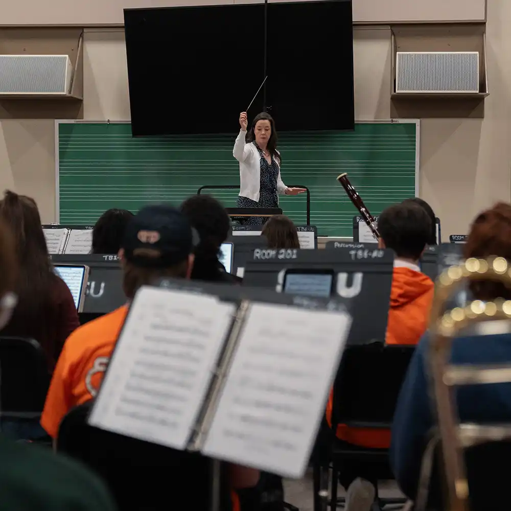 Two women looking at each other, smiling, sitting down, working on an assignment.
