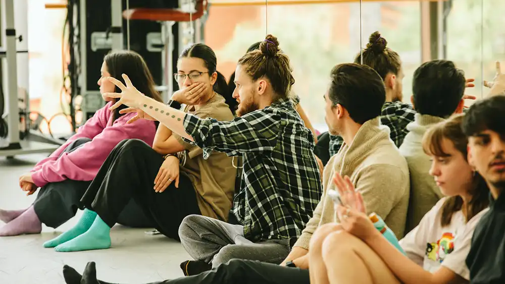 Professor speaking to the camera in a classroom style class, with her hands opened.