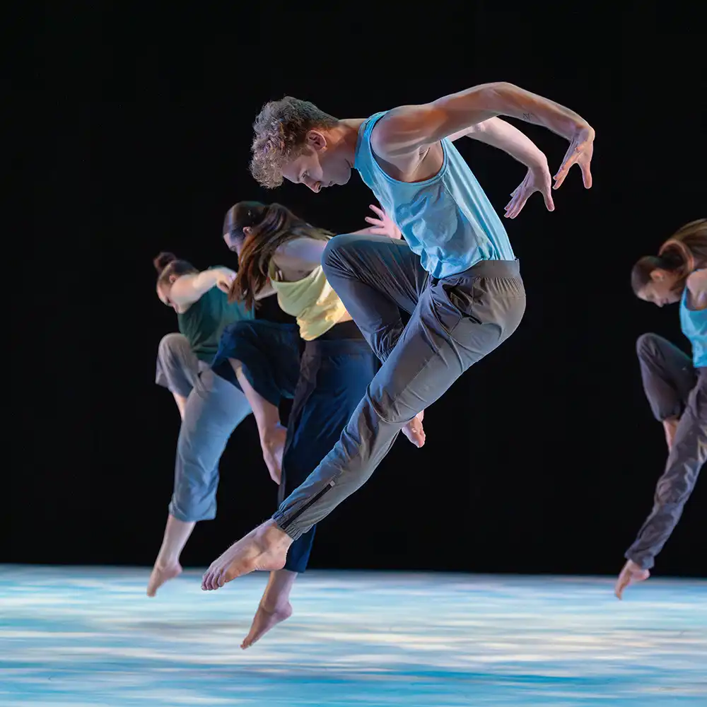 Two women looking at each other, smiling, sitting down, working on an assignment.