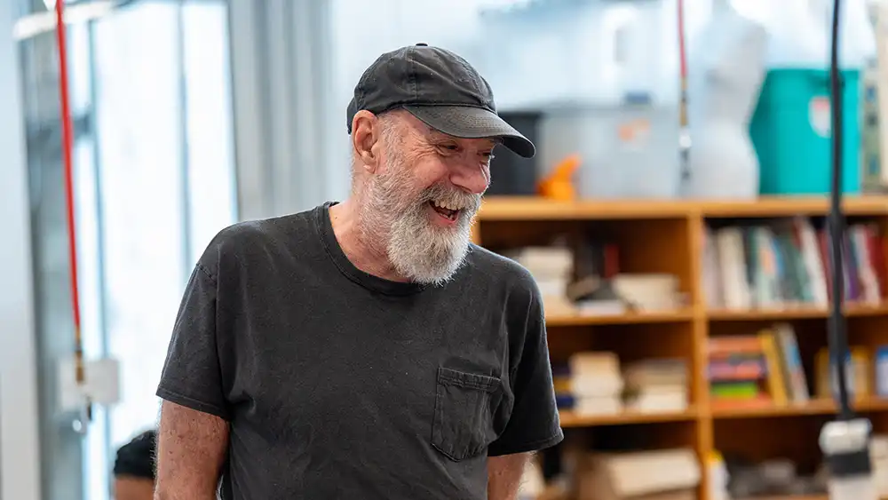 Professor speaking to the camera in a classroom style class, with her hands opened.