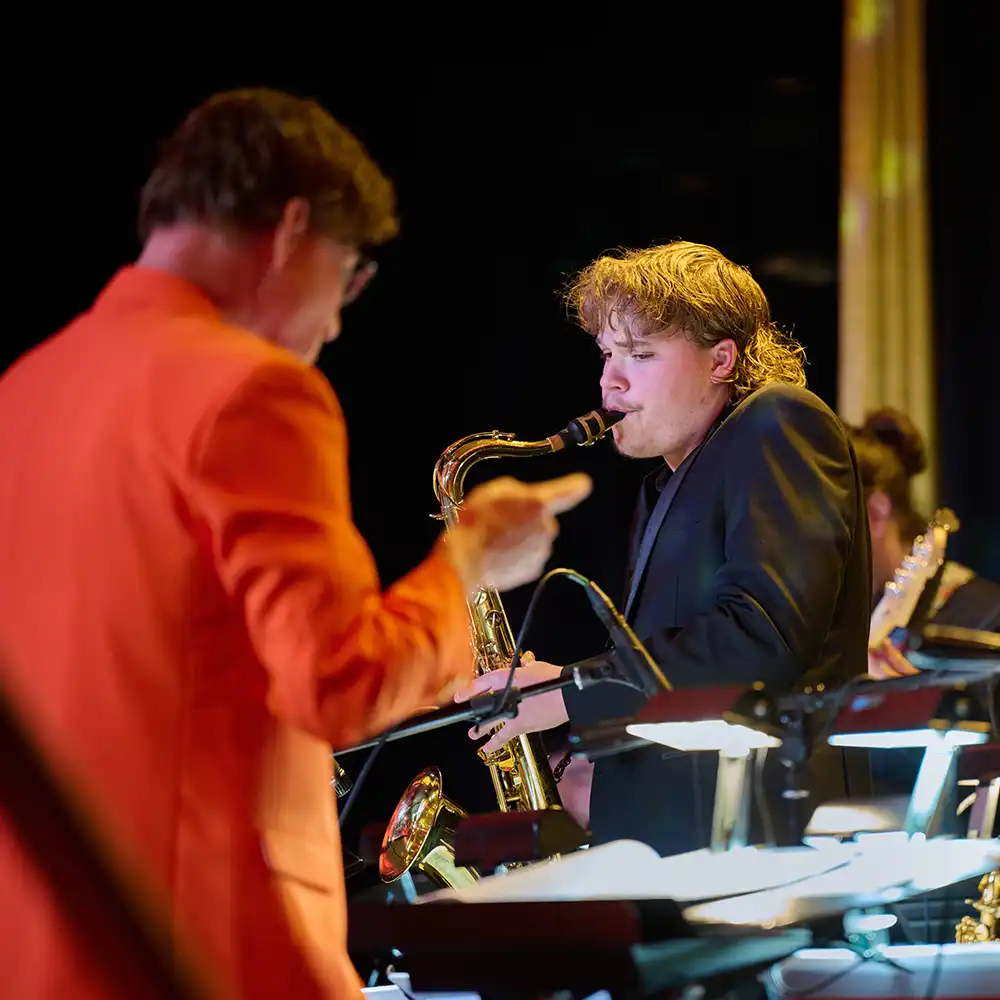Two women looking at each other, smiling, sitting down, working on an assignment.