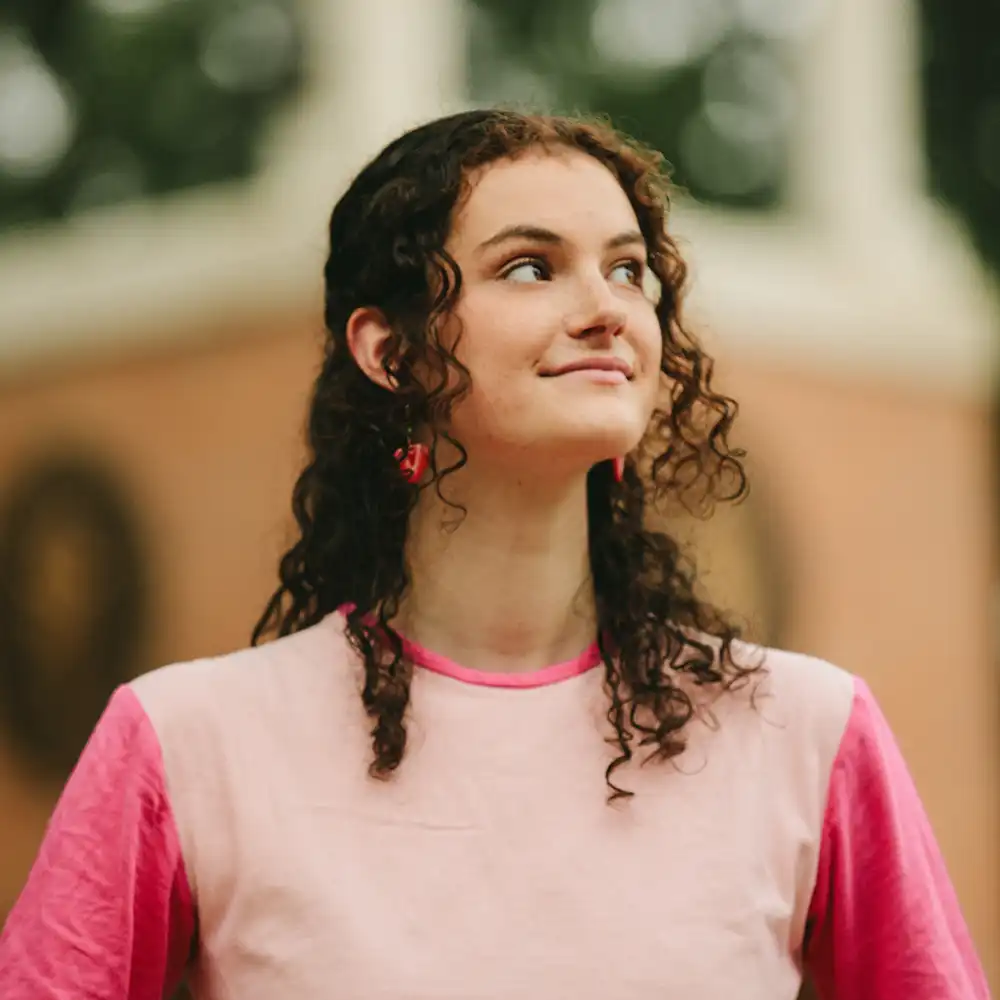 Student standing in front of clock tower on campus.