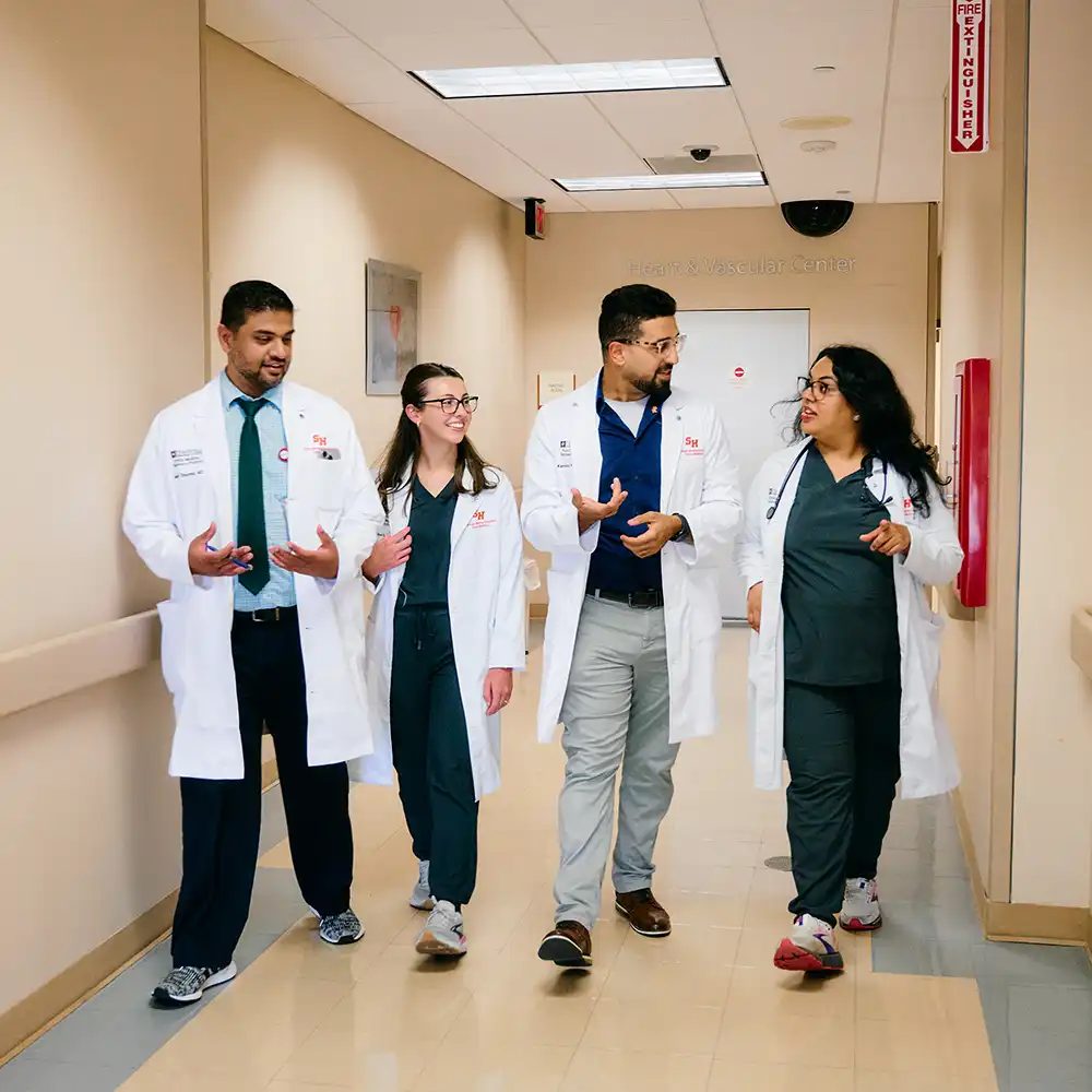 Medical students converse while walking down a hall.