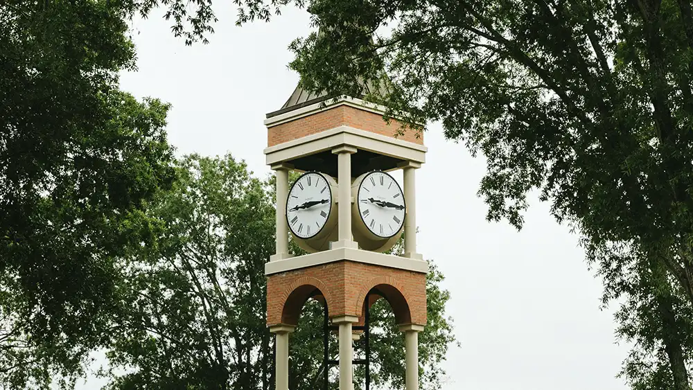Professor speaking to the camera in a classroom style class, with her hands opened.