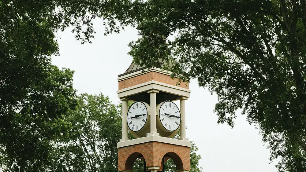 Professor speaking to the camera in a classroom style class, with her hands opened.