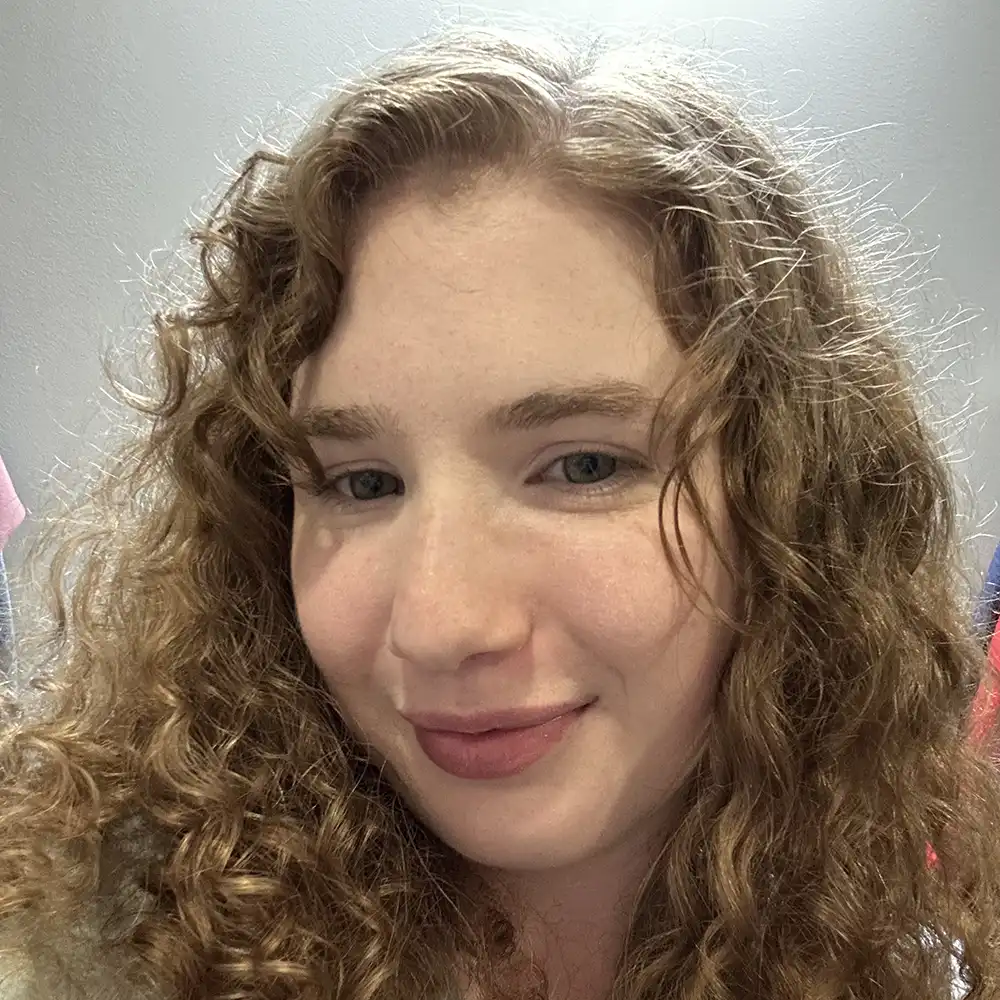 SHSU student smiles into the camera with curly hair framing their face.