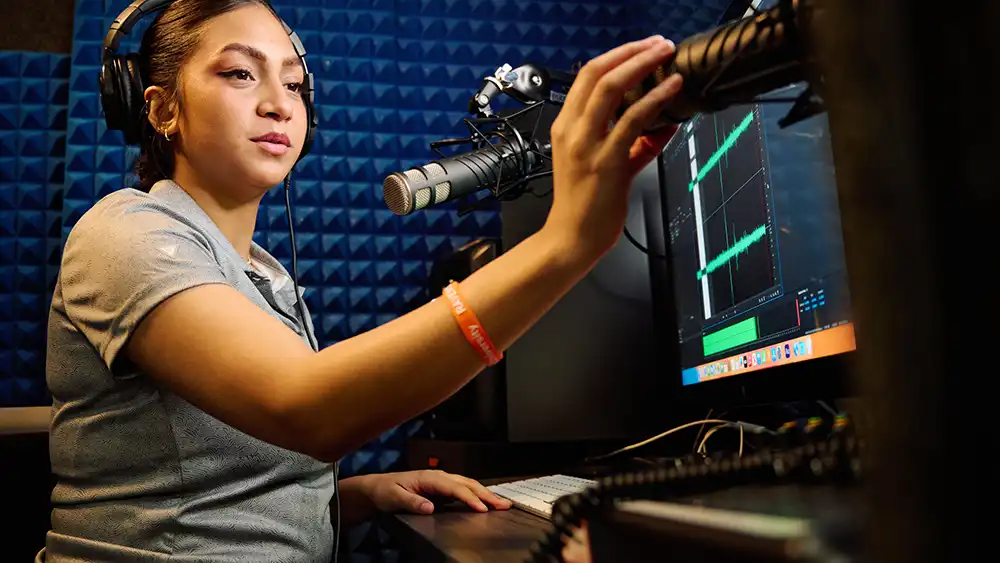 Professor speaking to the camera in a classroom style class, with her hands opened.