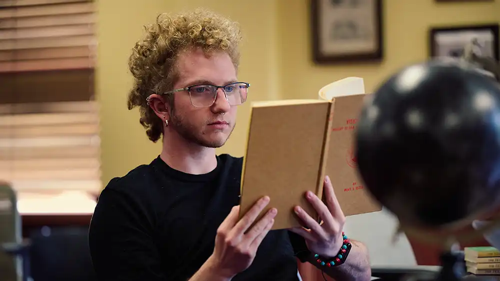 SHSU student holds a book, studying in Evan’s Complex.
