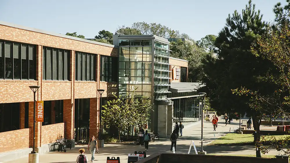 Professor speaking to the camera in a classroom style class, with her hands opened.
