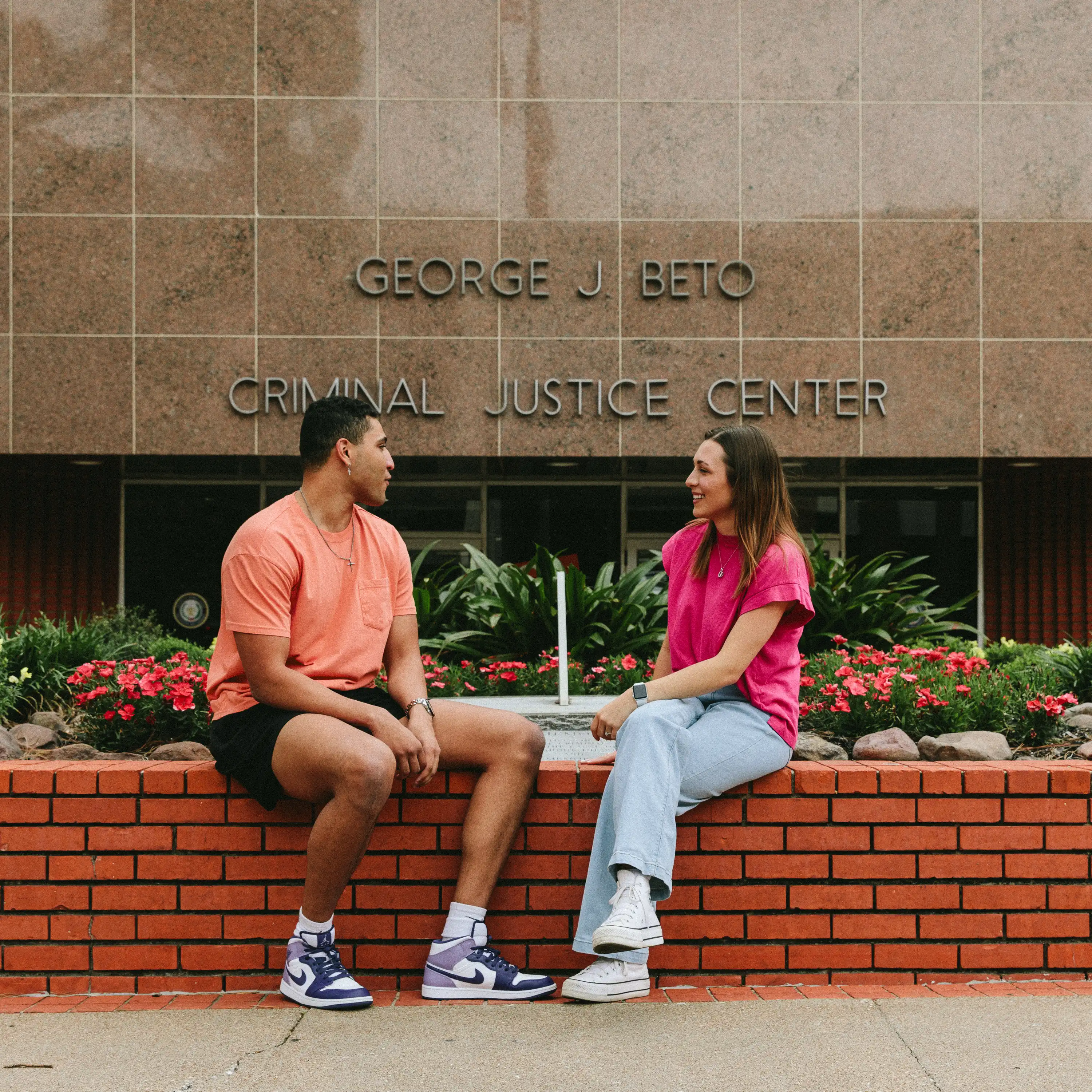 Man and woman sitting by sundial in front of an academic building.
