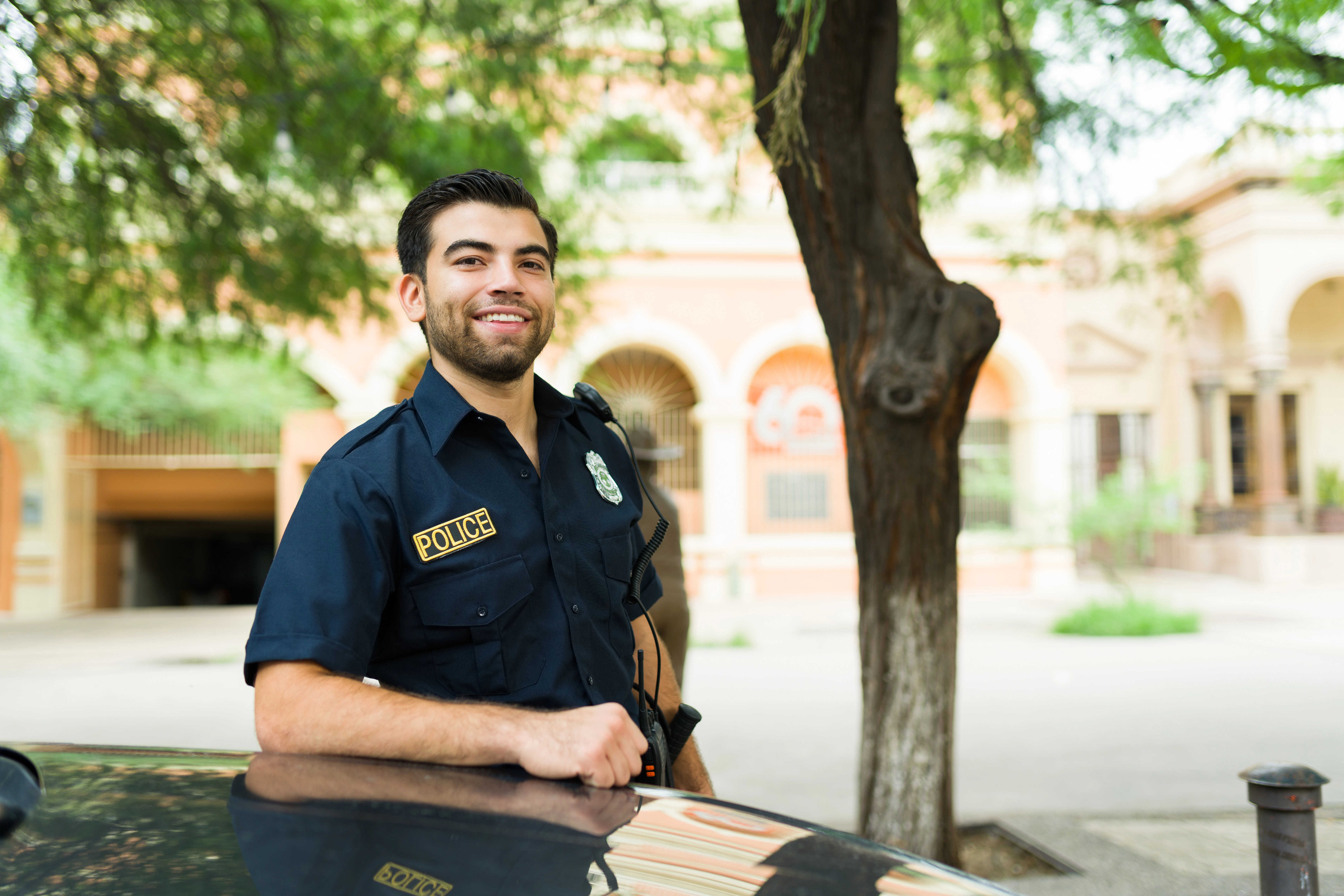 Police officer smiling and leaning on car