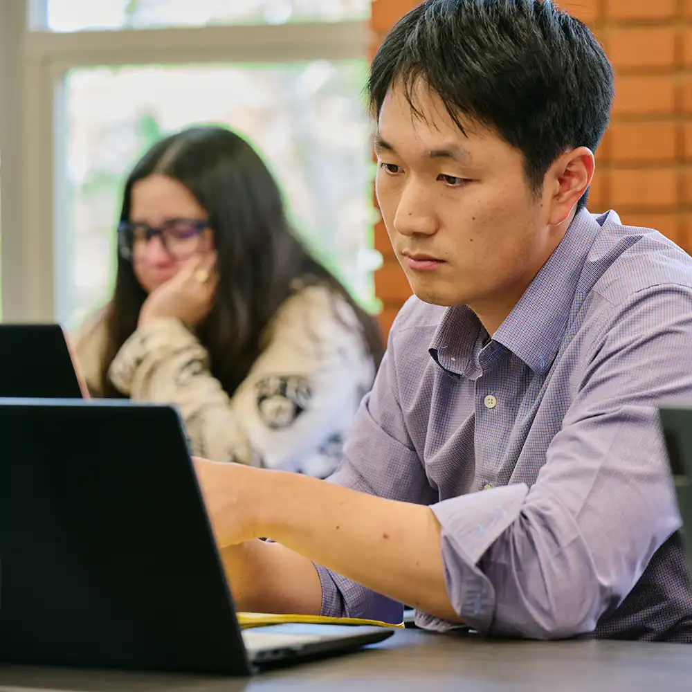 Graduate student working on laptop computer in classroom