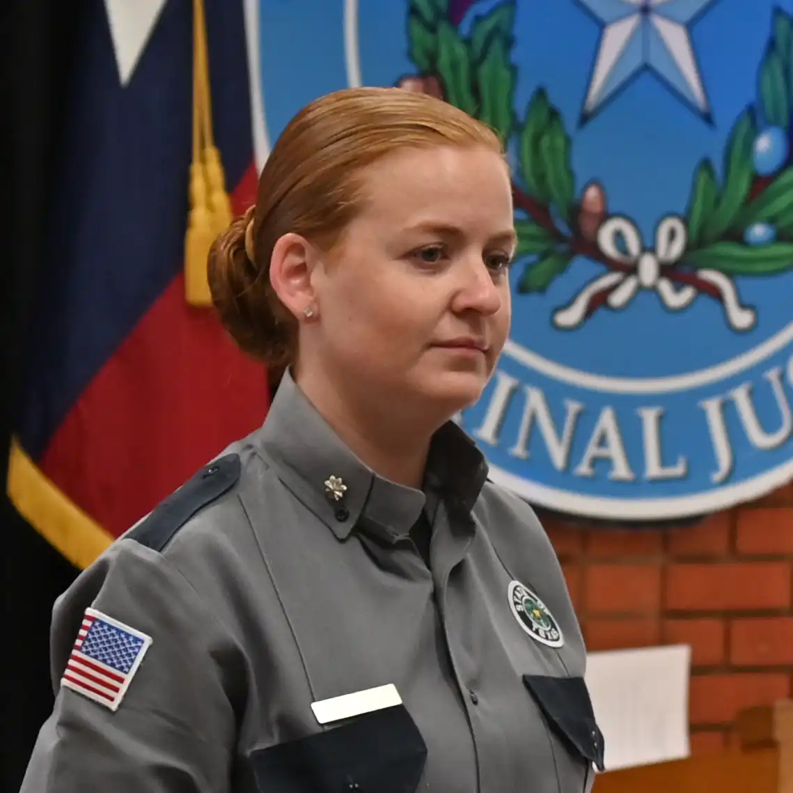 Woman in corrections officer uniform listening to speaker that is not in the photo.