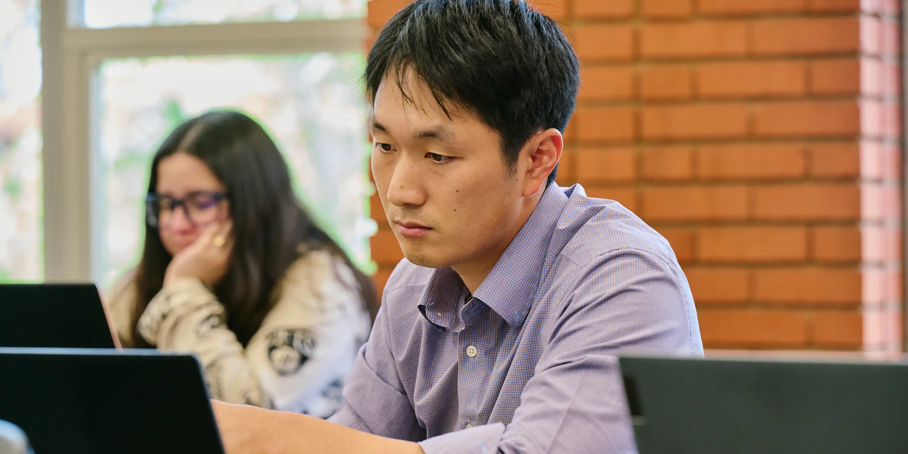 Graduate student working on laptop computer in classroom