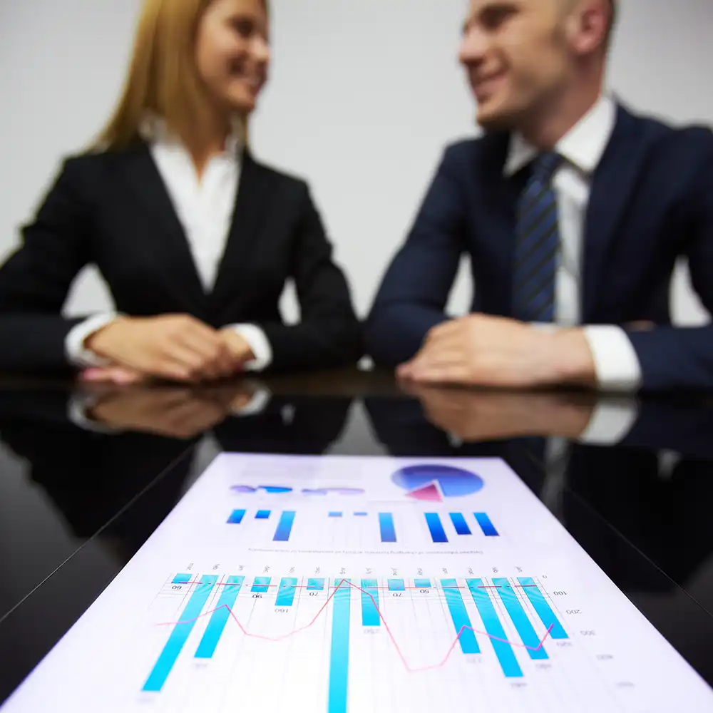 Two women looking at each other, smiling, sitting down, working on an assignment.
