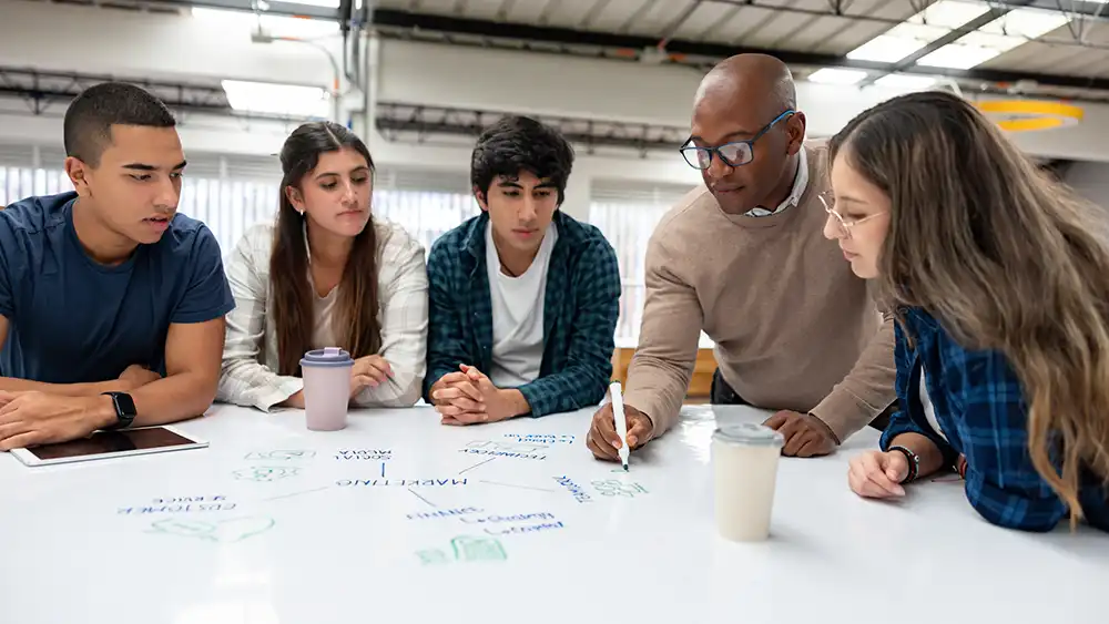 Professor working with students at a table.