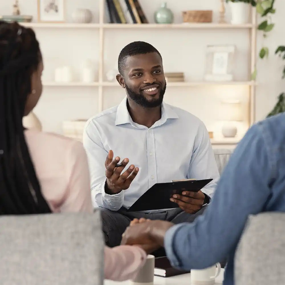 Two women looking at each other, smiling, sitting down, working on an assignment.