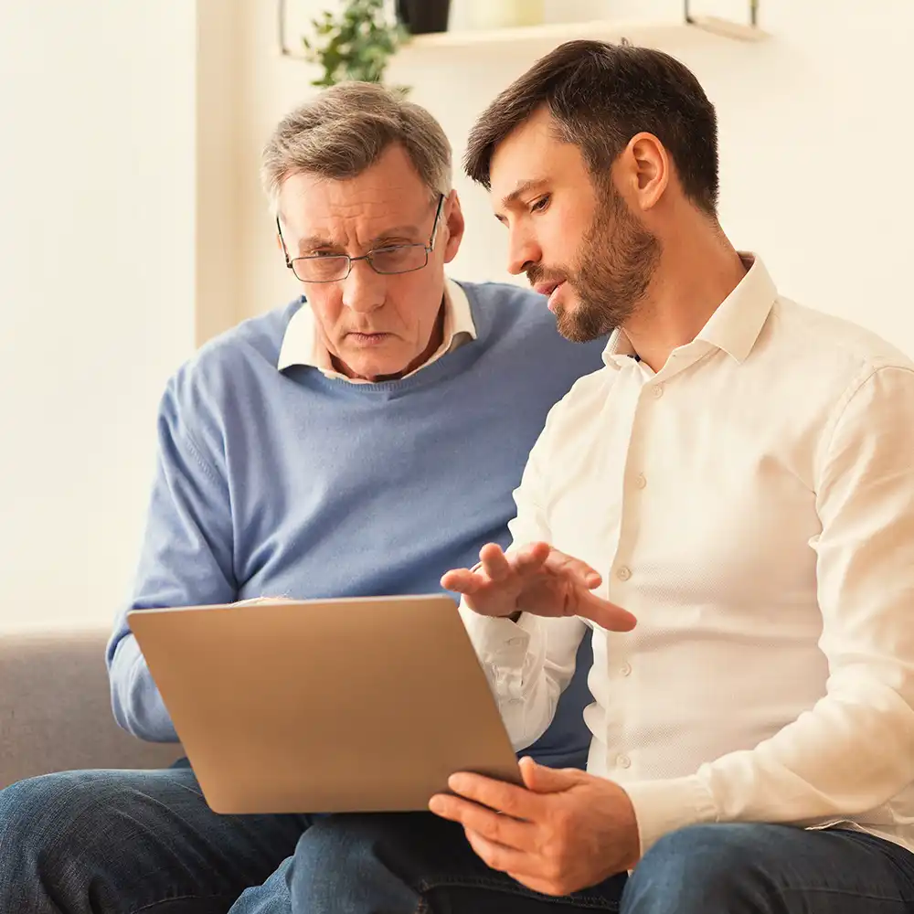 Two women looking at each other, smiling, sitting down, working on an assignment.