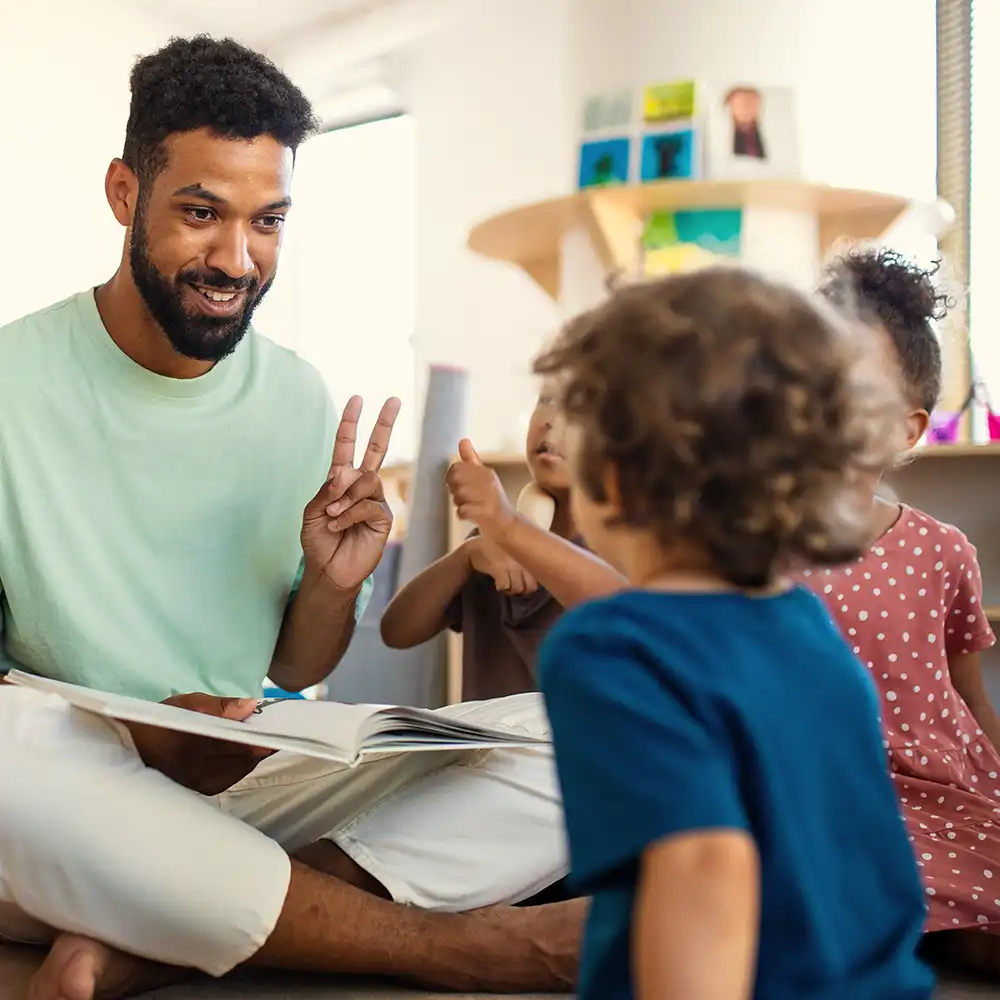 Two women looking at each other, smiling, sitting down, working on an assignment.