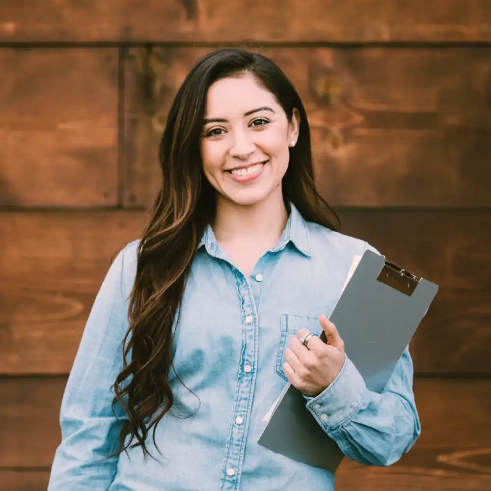 Two women looking at each other, smiling, sitting down, working on an assignment.