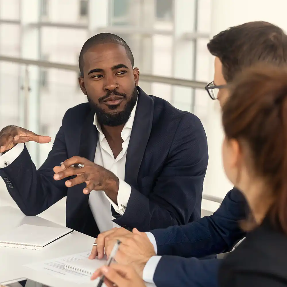Two women looking at each other, smiling, sitting down, working on an assignment.
