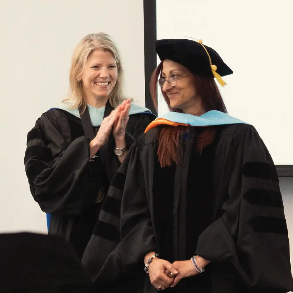 Lady in regalia clapping for another lady dressed in regalia