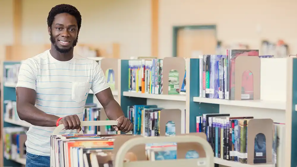 Man pushing cart filled of books 