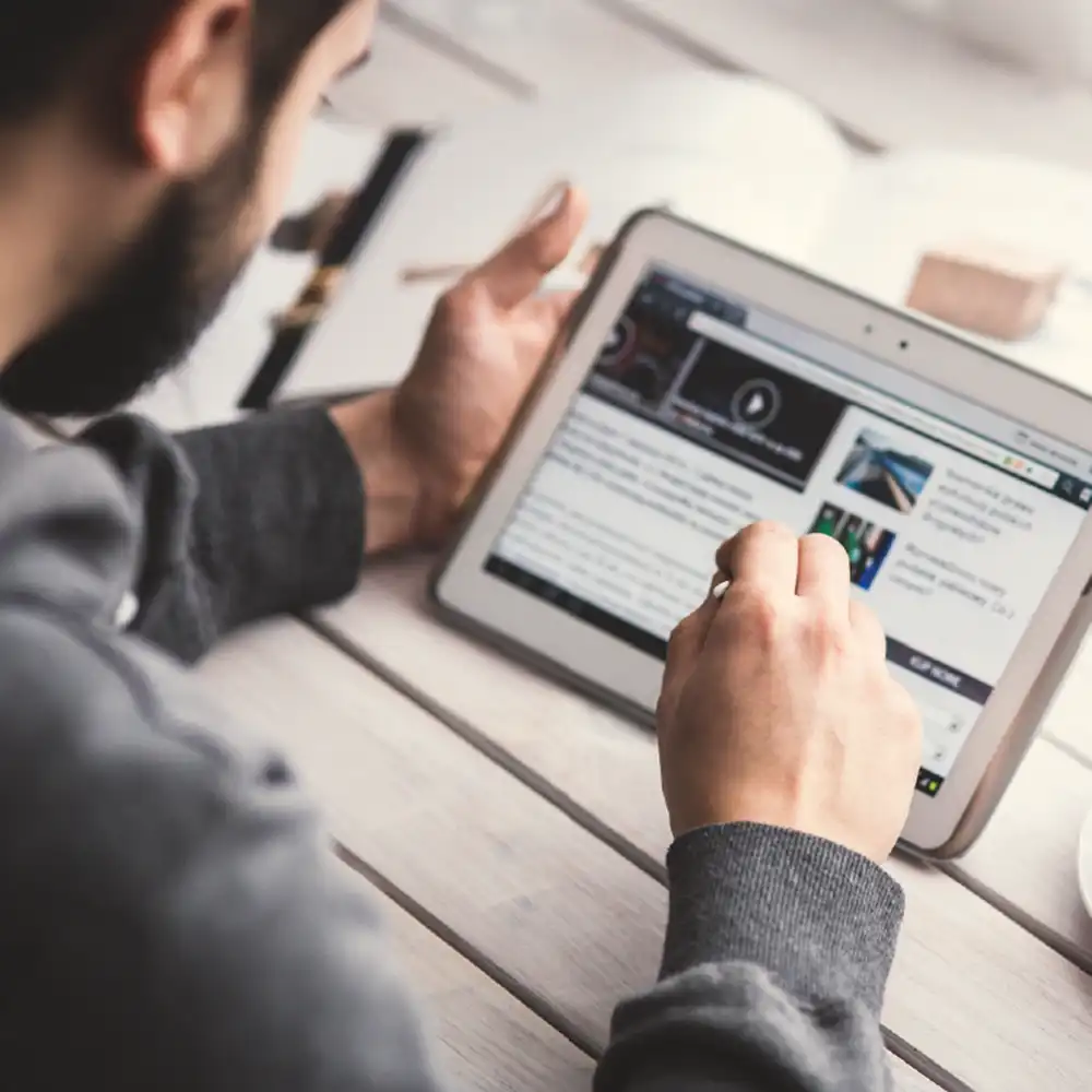 Lady sitting in an office setting wearing virtual reality goggles next a man using an iPad