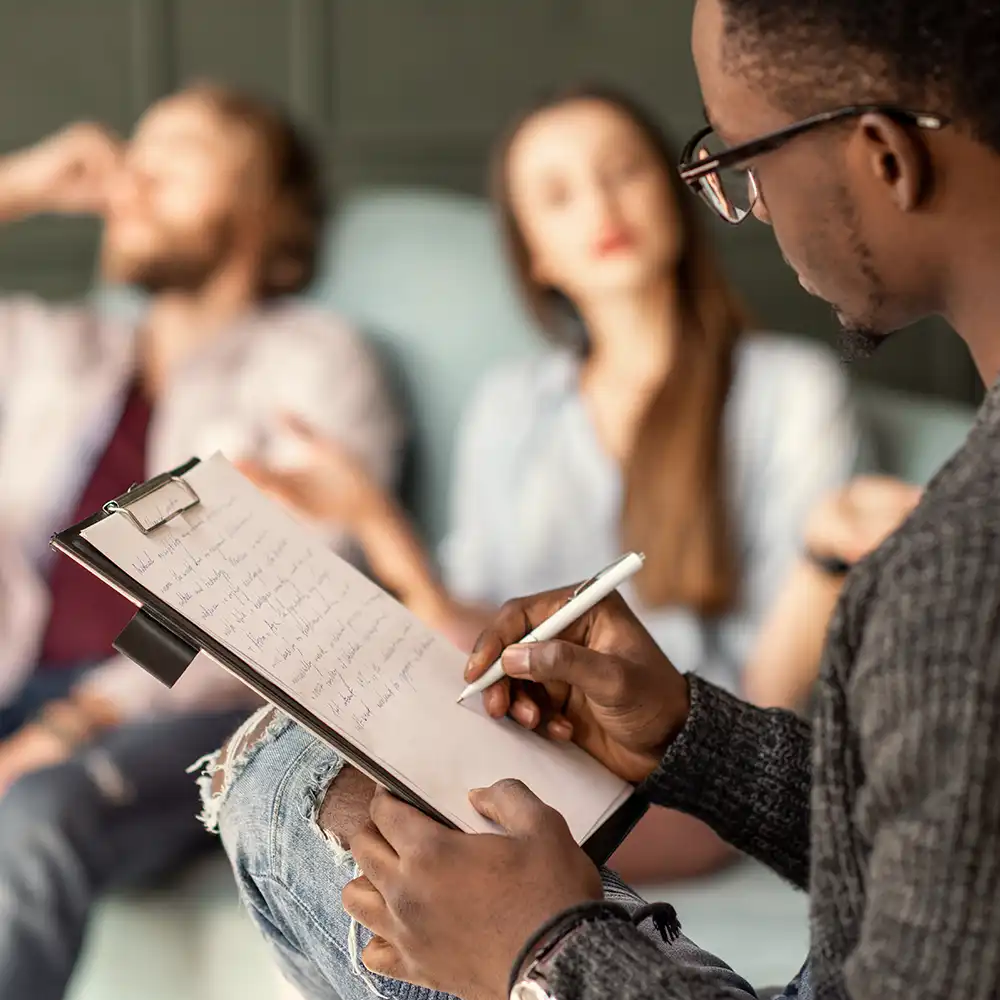 Two women looking at each other, smiling, sitting down, working on an assignment.