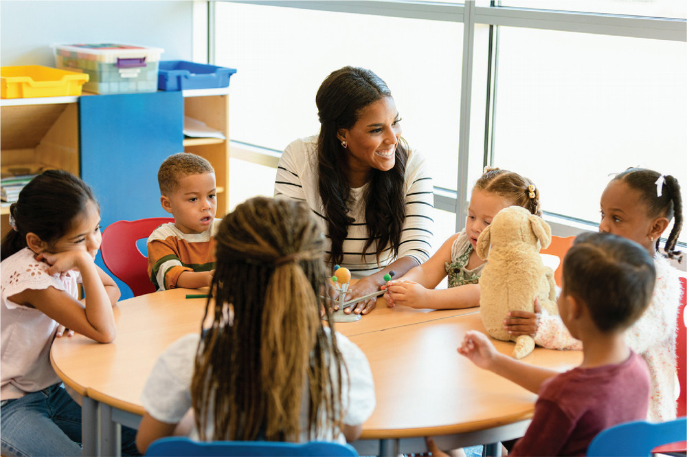 Woman sitting at a table with a group of elementary age students