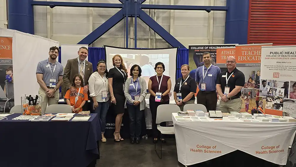 Professor speaking to the camera in a classroom style class, with her hands opened.