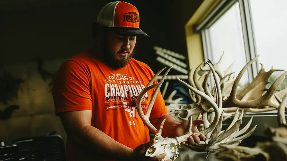 Man looking at a decomposed deer skull. 