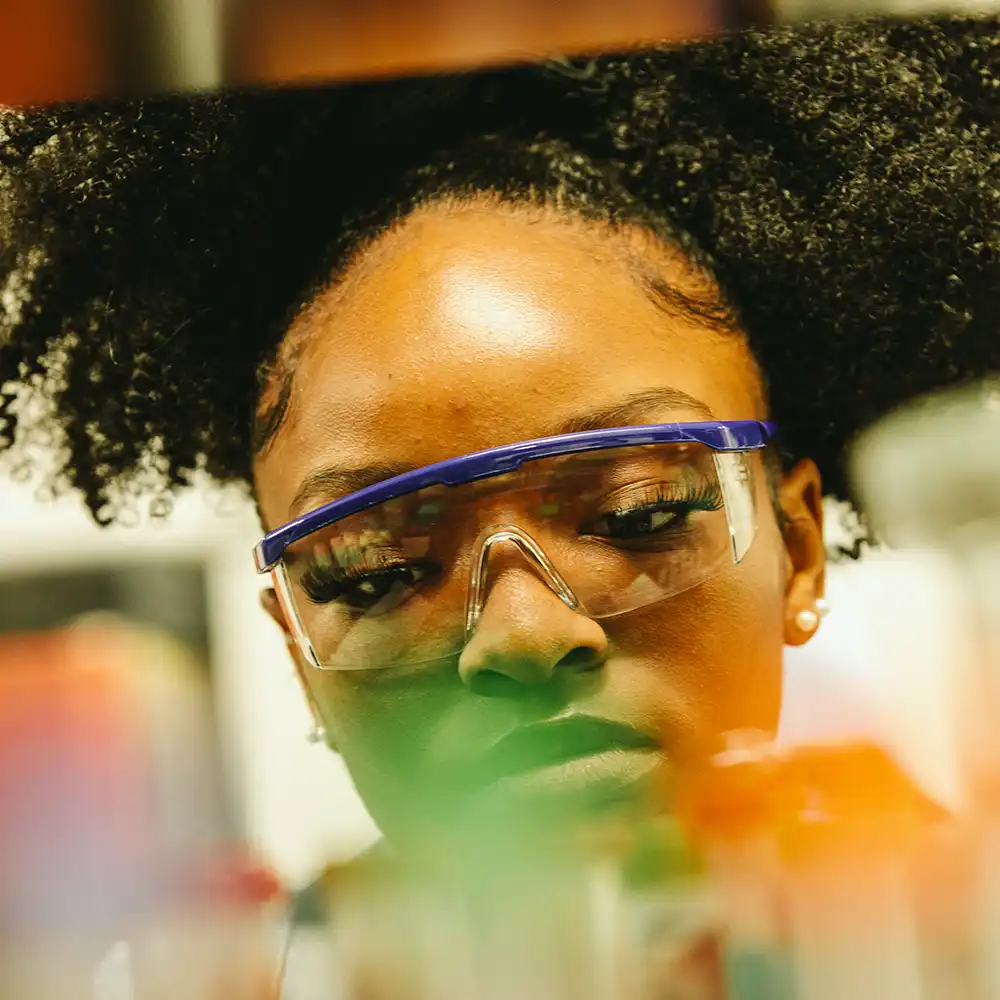 Woman working in a lab, wearing safety goggles