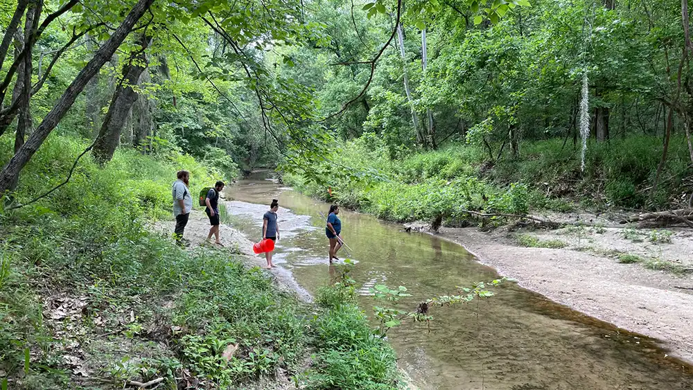 SHSU Students crossing a creek.