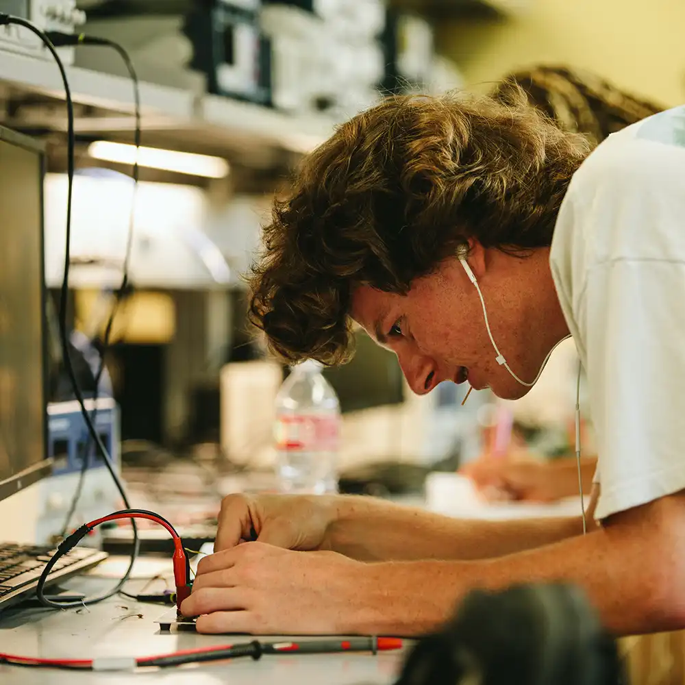Two women looking at each other, smiling, sitting down, working on an assignment.