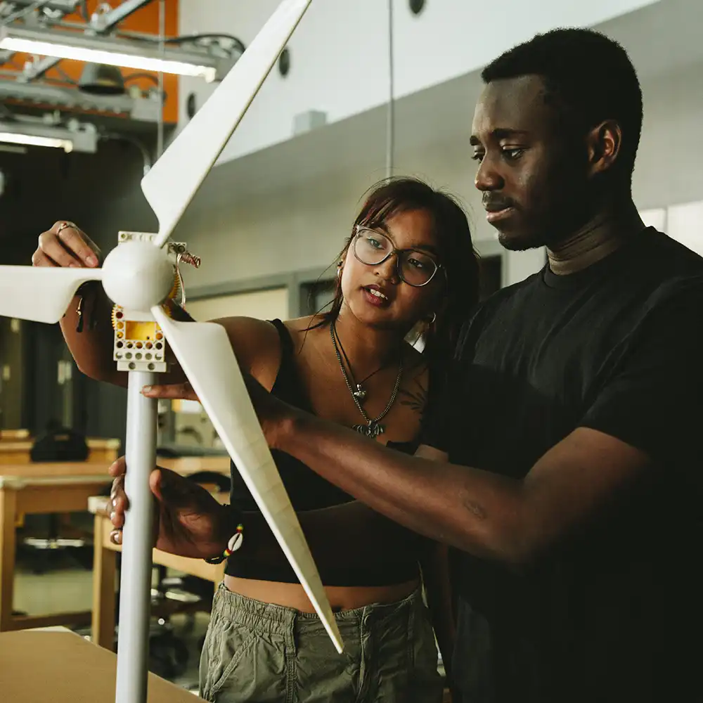Two women looking at each other, smiling, sitting down, working on an assignment.