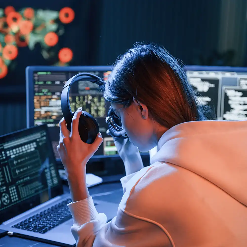 Woman looking at computer with her headphones on. 