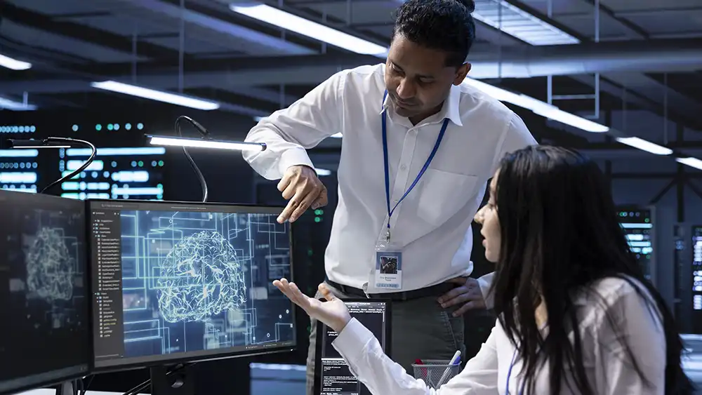 Professor speaking to a student in front of computer.