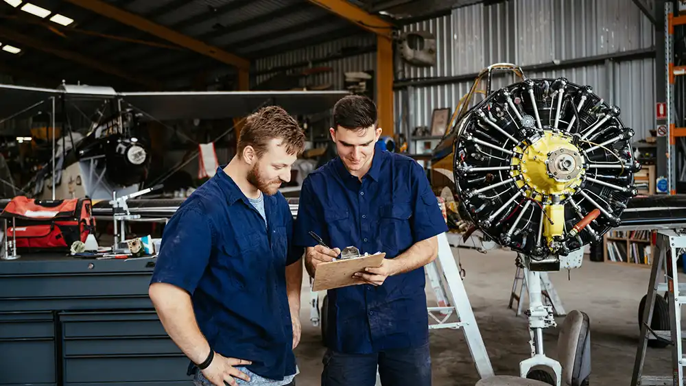 Two men working in an aerospace plant on a jet engine. 