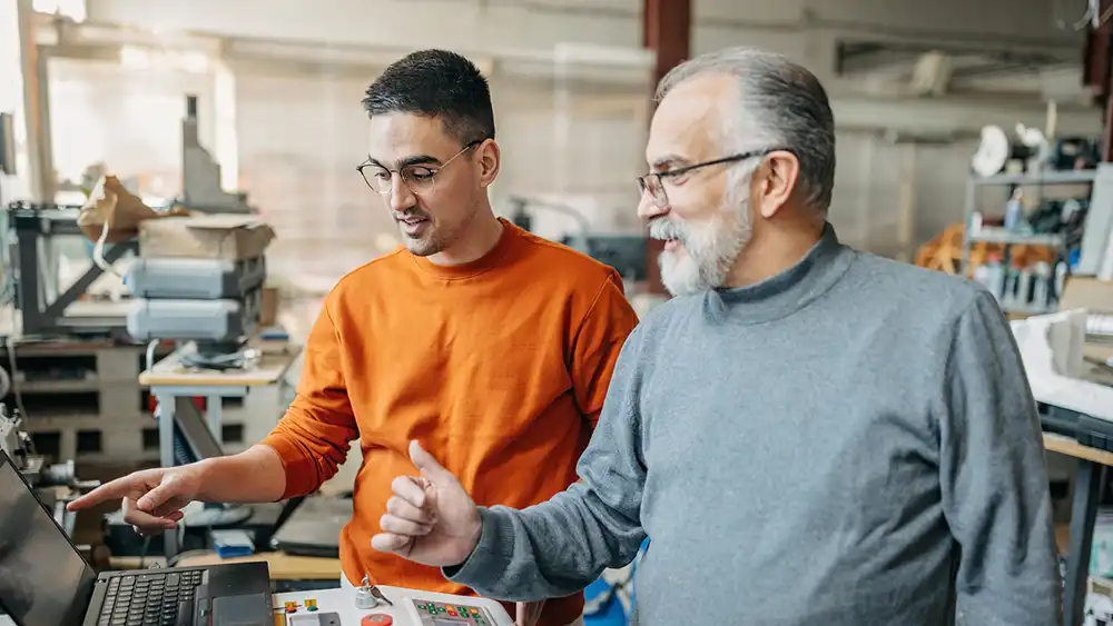 Professor and male student working on a manufacturing terminal. 