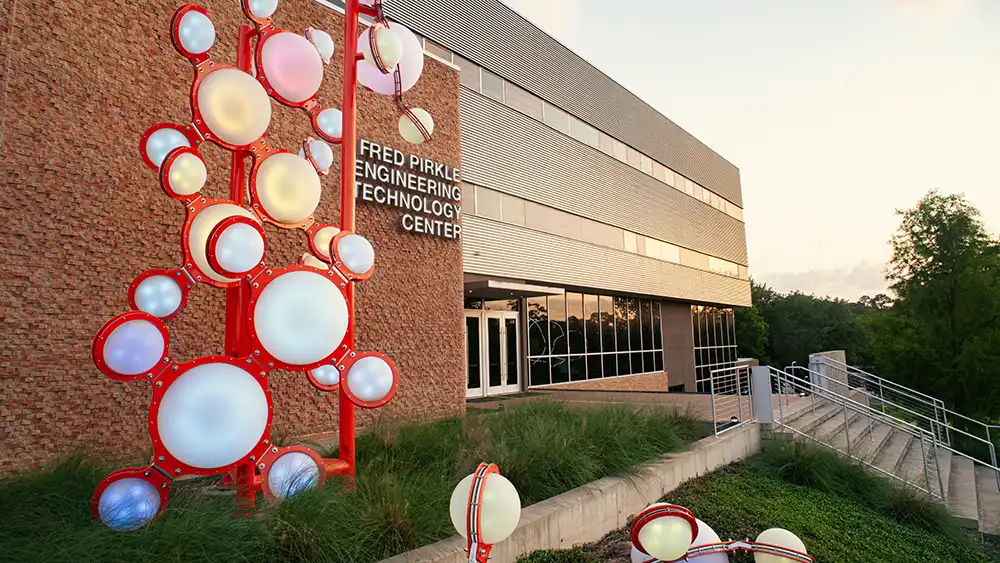 Professor speaking to the camera in a classroom style class, with her hands opened.