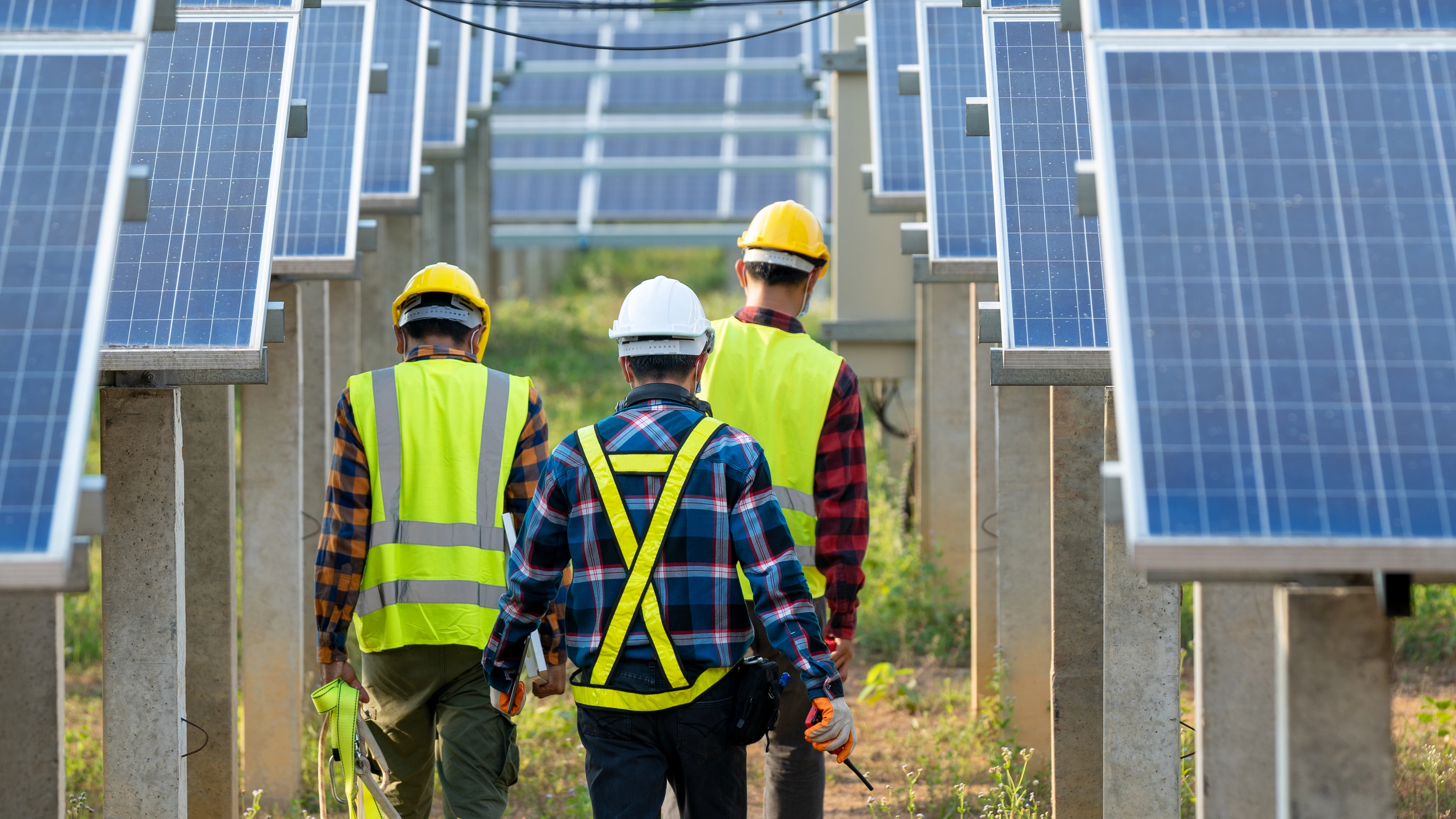 Safety workers walking through rows of solar panels. 
