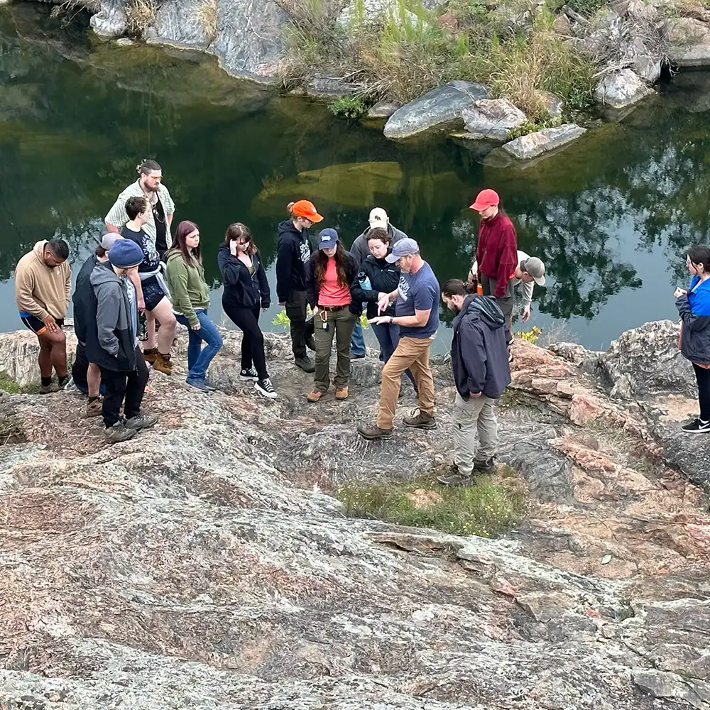 Two women looking at each other, smiling, sitting down, working on an assignment.