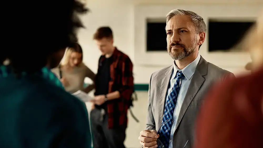 Professor speaking to the camera in a classroom style class, with her hands opened.