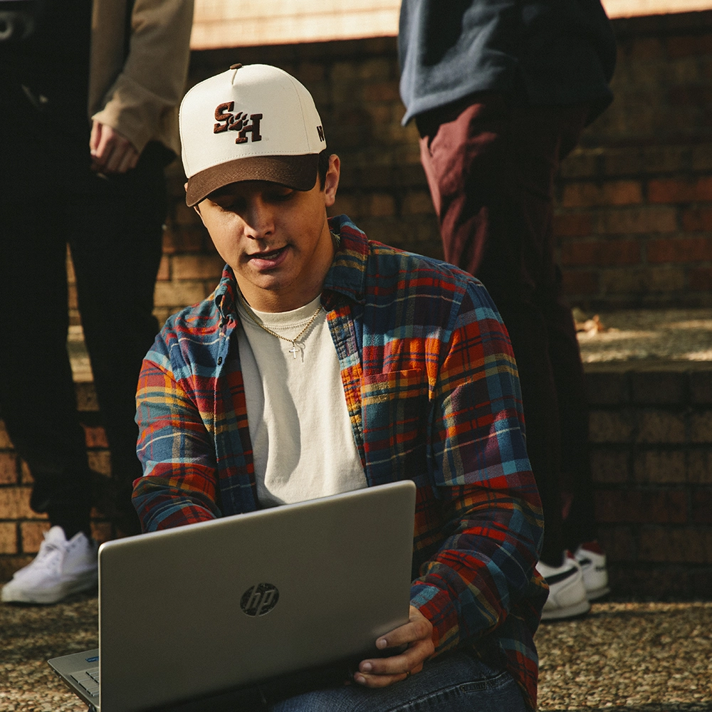 SHSU student working on a laptop, talking with other people