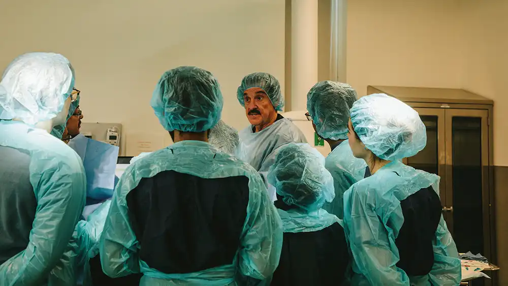 Professor speaking to the camera in a classroom style class, with her hands opened.